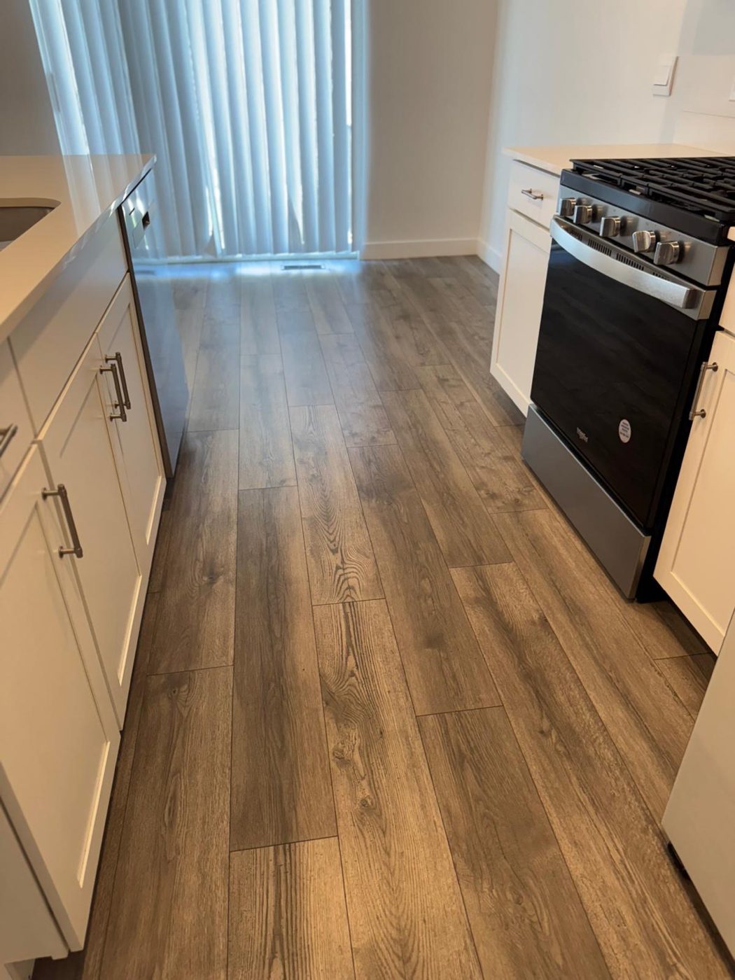 Mopped kitchen floor with clean wood-look planks beside a spotless range and cabinets