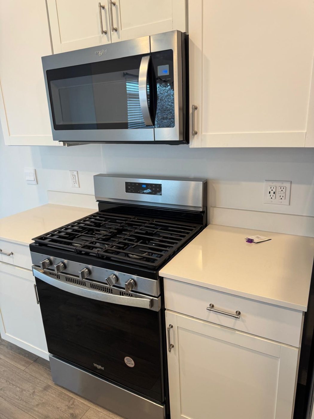 Clean stainless gas range and over-the-range microwave with polished white countertops after a kitchen deep cleaning