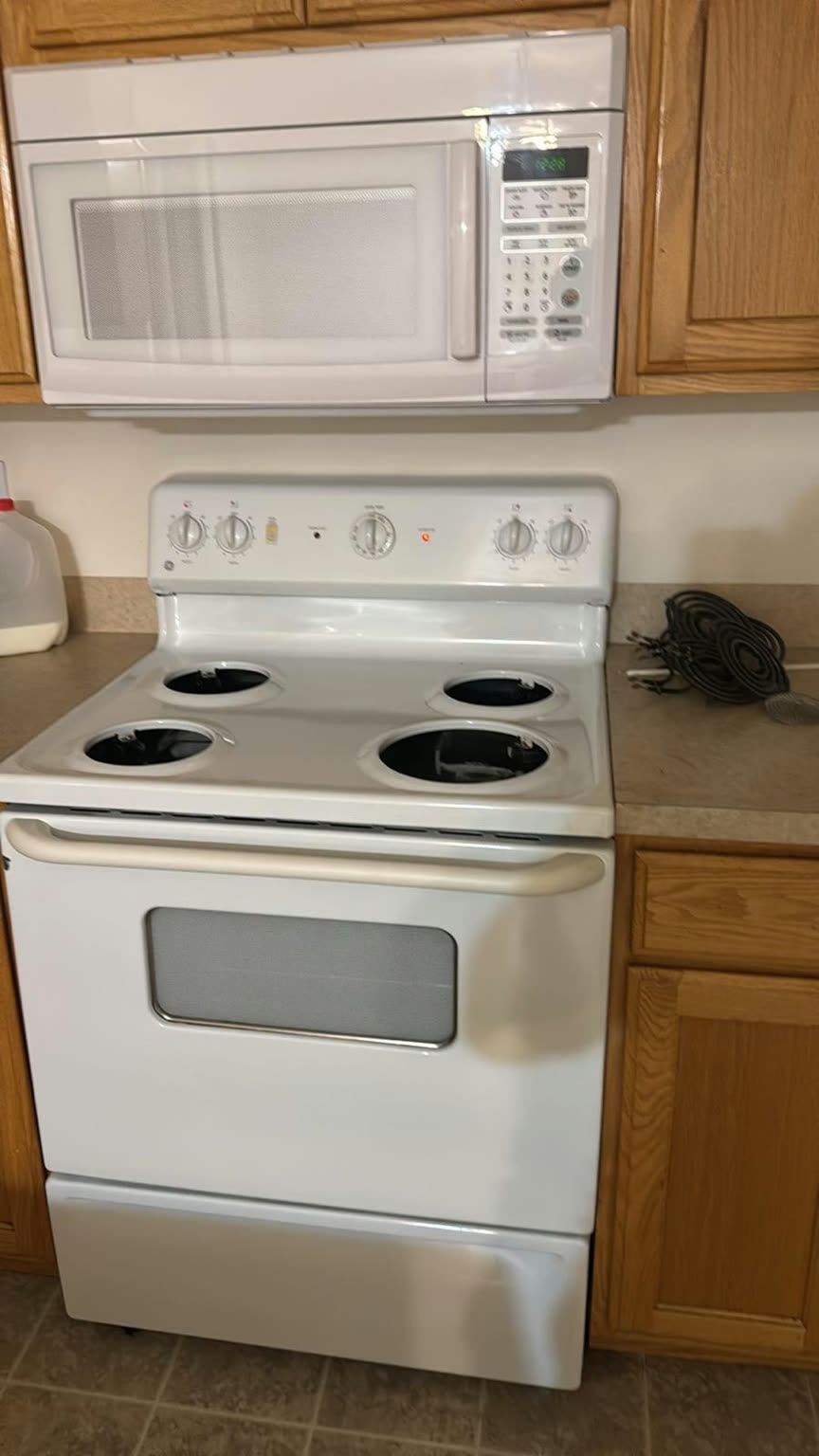 The same electric range after cleaning, with a bright white cooktop, clean burner wells, and a spotless control panel
