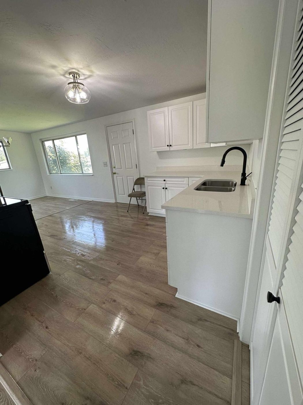Empty living area and kitchen fully cleaned for move-in, with polished floors and wiped white cabinetry