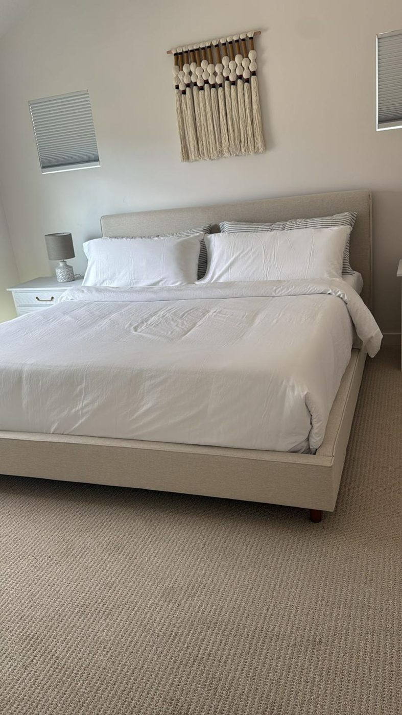 Bedroom cleaned and prepared with crisp white bedding, dusted nightstand, and vacuumed carpet