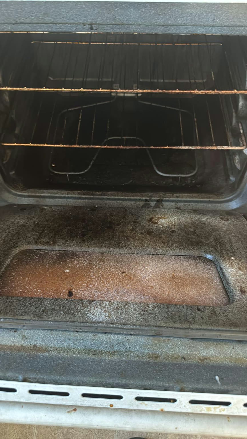 Oven interior before cleaning, coated with baked-on grease, burnt carbon buildup, and rusted racks